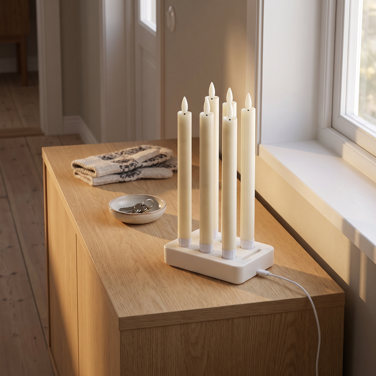 Velas ladestation med alle seks kronelys på en kommode i entréen, USB-C-kablet sat i